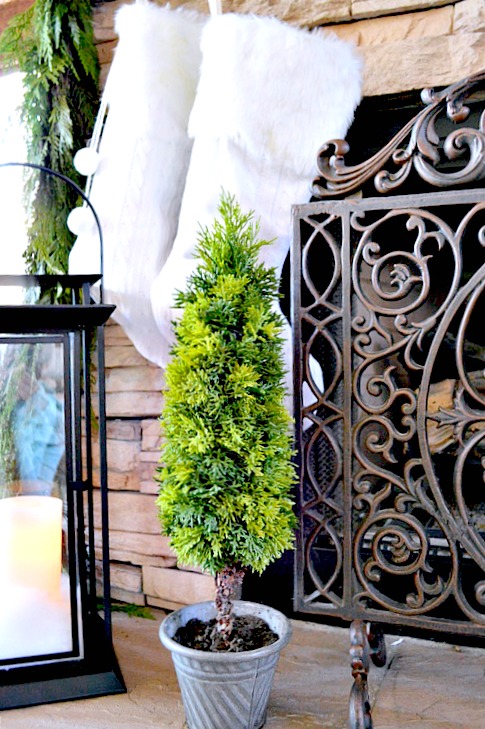 Stacked Stone fireplace with topiary and white knitted stockings with lantern, so pretty